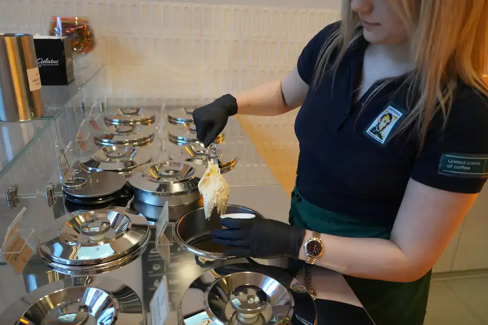 Artisan gelato being freshly scooped from a stainless steel pan
